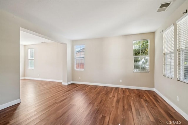 empty room with dark wood-type flooring and a wealth of natural light