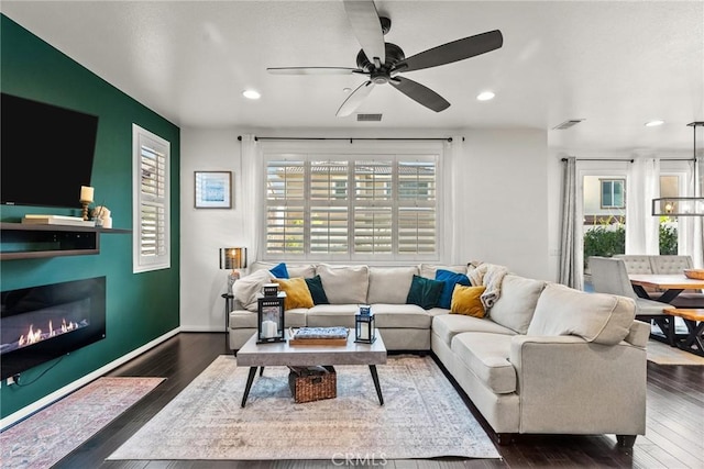 living room featuring ceiling fan, a healthy amount of sunlight, and dark hardwood / wood-style floors