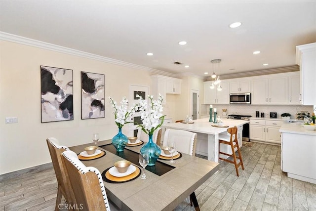 dining area with sink, light wood-type flooring, and crown molding