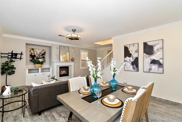 dining area featuring ornamental molding and light hardwood / wood-style flooring