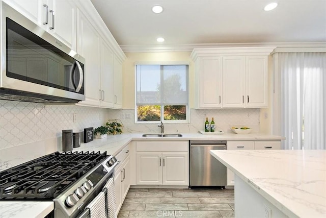 kitchen with light stone countertops, tasteful backsplash, white cabinets, appliances with stainless steel finishes, and sink