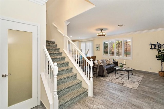 staircase with wood-type flooring and crown molding