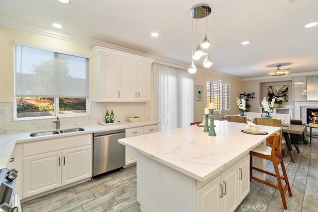 kitchen featuring sink, white cabinets, dishwasher, a kitchen island, and pendant lighting