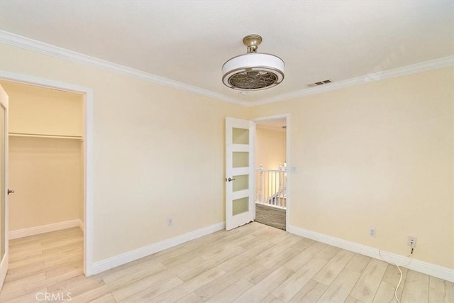 unfurnished bedroom with light hardwood / wood-style flooring, a spacious closet, a closet, and crown molding