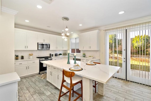 kitchen featuring a center island with sink, white cabinetry, pendant lighting, and appliances with stainless steel finishes