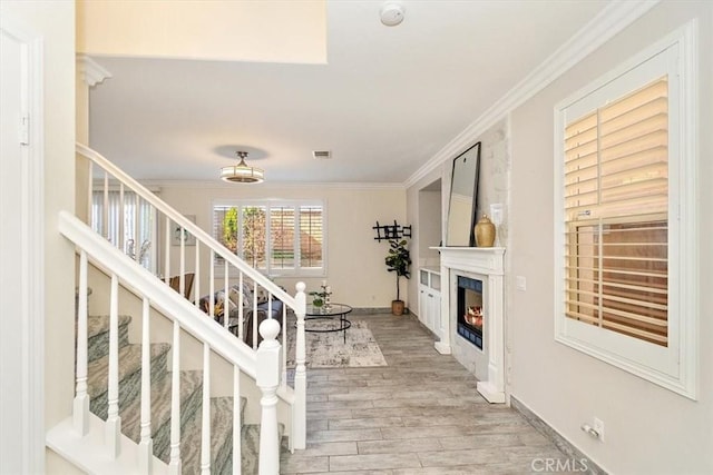 staircase with ornamental molding and hardwood / wood-style floors