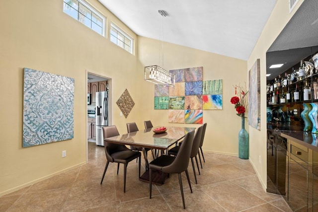 tiled dining area featuring a towering ceiling and a notable chandelier