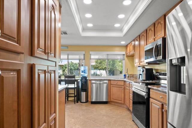 kitchen featuring stainless steel appliances, sink, light tile patterned floors, a tray ceiling, and crown molding