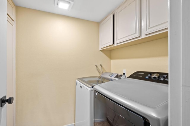 clothes washing area featuring cabinets and washer and clothes dryer