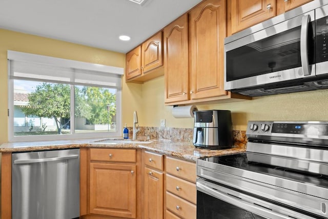 kitchen featuring light stone countertops, appliances with stainless steel finishes, and sink