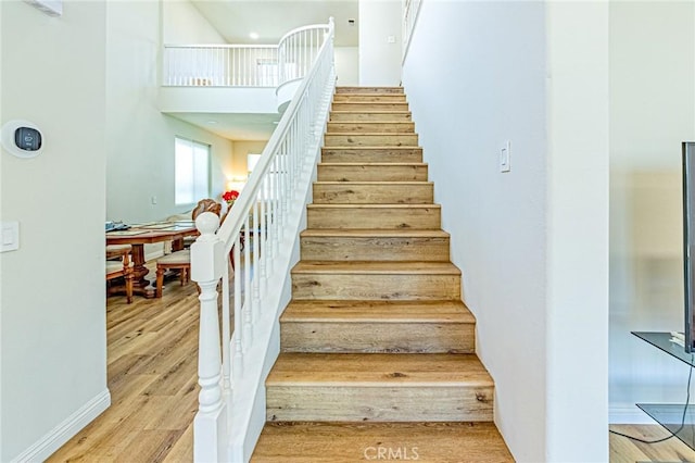 stairway with a towering ceiling and hardwood / wood-style flooring