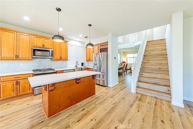 kitchen with stainless steel appliances, light hardwood / wood-style floors, backsplash, a kitchen island, and pendant lighting