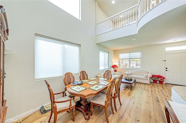 dining space with a towering ceiling and light hardwood / wood-style floors