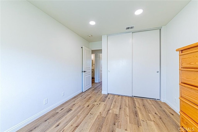 unfurnished bedroom with light wood-type flooring and a closet