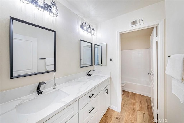 full bathroom with toilet, wood-type flooring, vanity, and shower / washtub combination