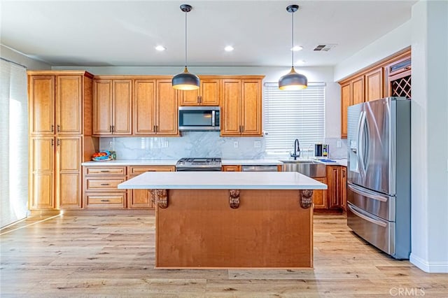 kitchen with pendant lighting, stainless steel appliances, tasteful backsplash, a kitchen island, and sink