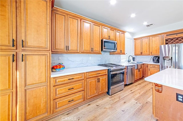 kitchen with stainless steel appliances, light hardwood / wood-style floors, backsplash, and sink