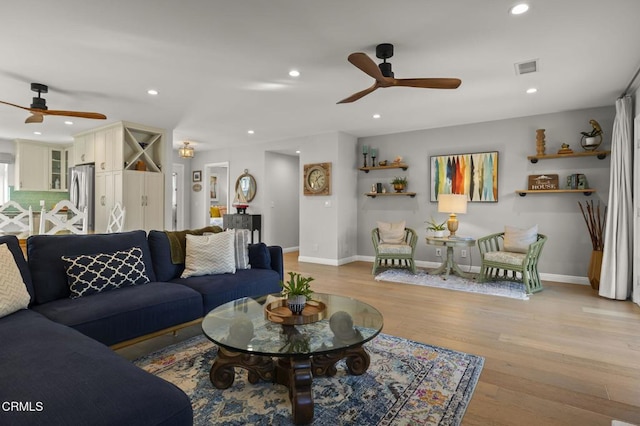 living room with ceiling fan and light hardwood / wood-style flooring