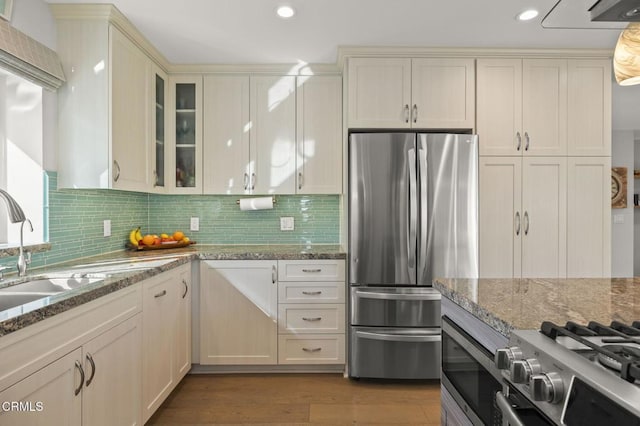 kitchen with sink, stainless steel appliances, light stone countertops, and cream cabinetry