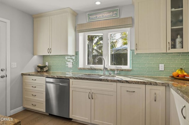 kitchen featuring light stone counters, stainless steel dishwasher, light wood-type flooring, cream cabinetry, and sink