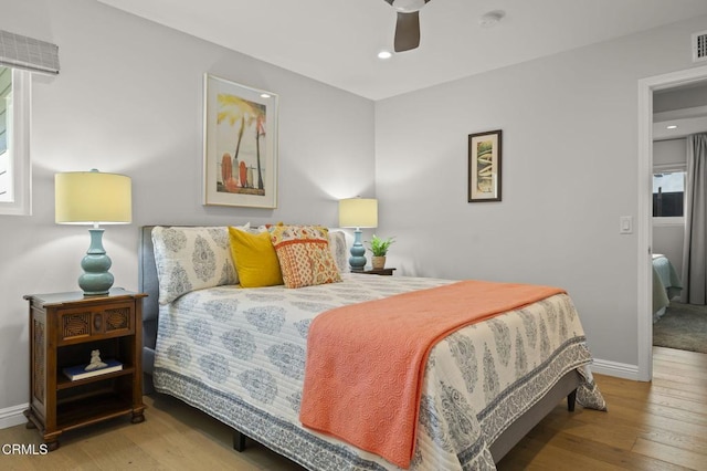 bedroom with ceiling fan, multiple windows, and wood-type flooring