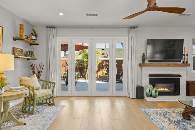 interior space with a fireplace, ceiling fan, and light hardwood / wood-style flooring