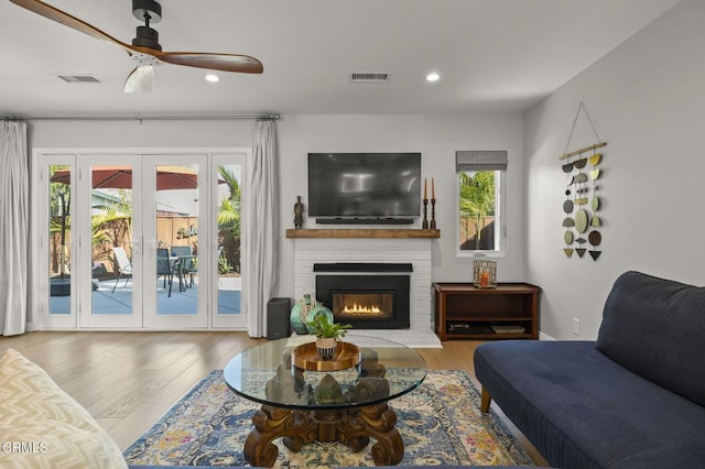 living room with french doors, a fireplace, ceiling fan, and hardwood / wood-style flooring