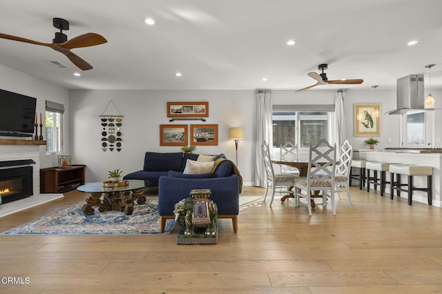 living room featuring ceiling fan, light hardwood / wood-style floors, and plenty of natural light