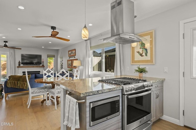 kitchen featuring island exhaust hood, stainless steel appliances, light stone countertops, light hardwood / wood-style flooring, and decorative light fixtures