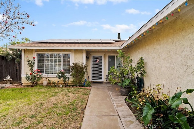 property entrance featuring a lawn and solar panels