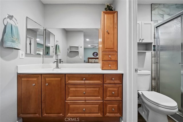 bathroom featuring vanity, a shower with door, and toilet