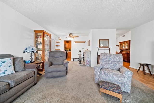 living room with wood-type flooring, ceiling fan, and a textured ceiling