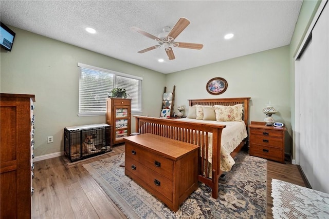 bedroom featuring ceiling fan, light hardwood / wood-style flooring, and a textured ceiling