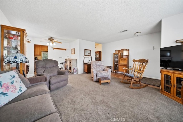 carpeted living room with ceiling fan and a textured ceiling