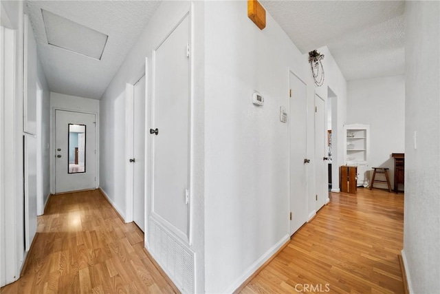 hall with light hardwood / wood-style floors and a textured ceiling