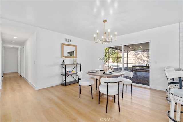 dining space featuring light hardwood / wood-style floors and an inviting chandelier