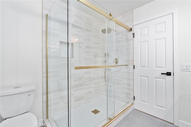 bathroom featuring toilet and a shower with shower door