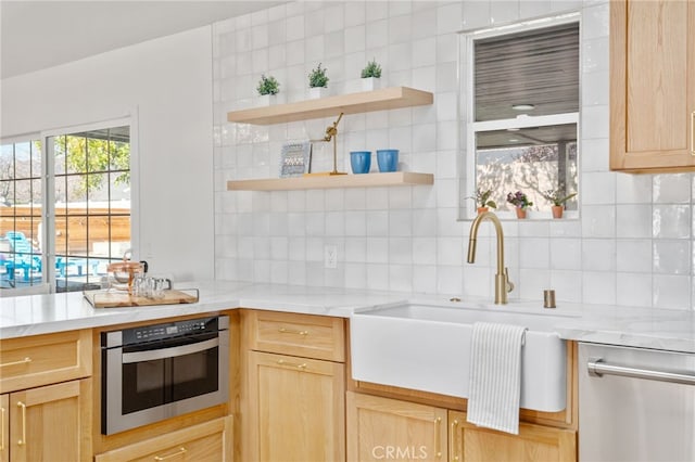 kitchen with appliances with stainless steel finishes, light brown cabinetry, tasteful backsplash, and sink