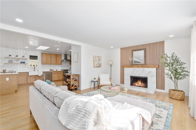 living room featuring sink, a high end fireplace, and light hardwood / wood-style flooring