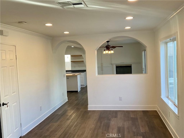 empty room with dark hardwood / wood-style flooring, ornamental molding, and ceiling fan