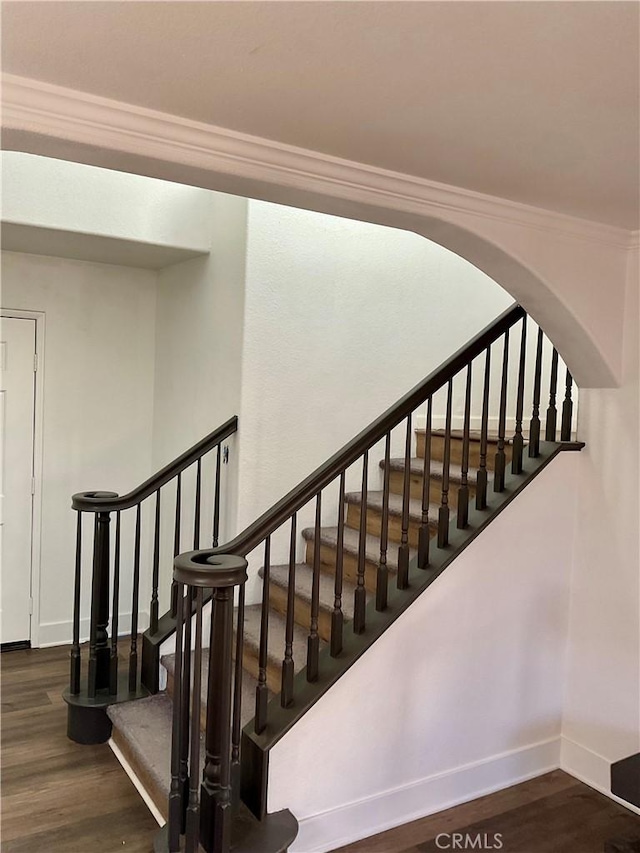 stairway with ornamental molding and hardwood / wood-style floors