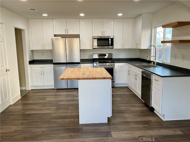 kitchen featuring sink, wooden counters, stainless steel appliances, white cabinets, and a kitchen island