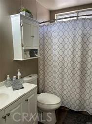 bathroom with toilet, a shower with shower curtain, and vanity