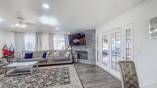 living room with a stone fireplace, french doors, wood finished floors, and crown molding