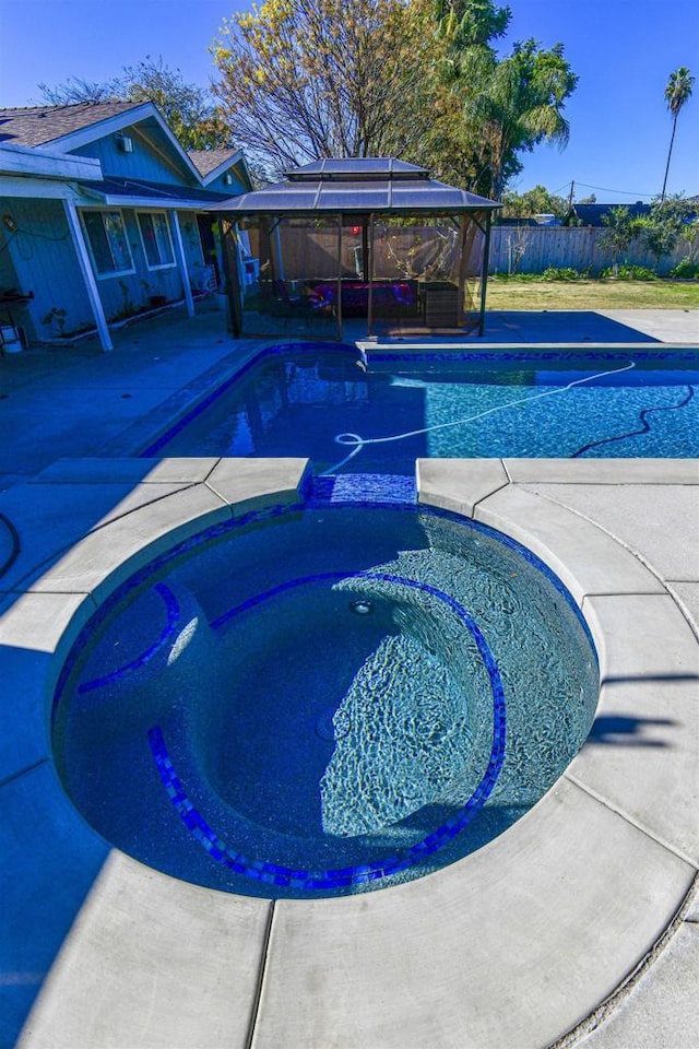 view of pool featuring a patio area, a pool with connected hot tub, and fence