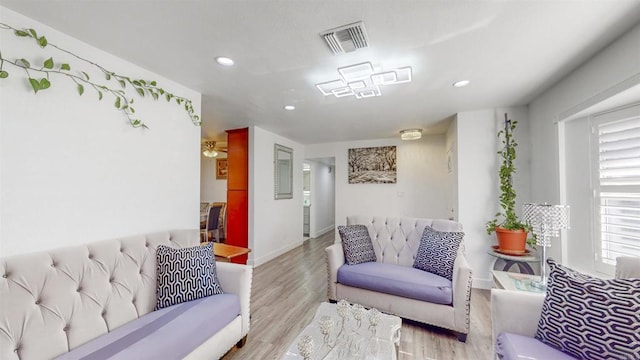 living room with light wood-type flooring, baseboards, visible vents, and recessed lighting