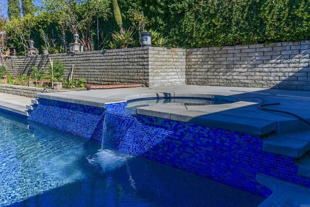 view of swimming pool with fence, a fenced in pool, and an in ground hot tub