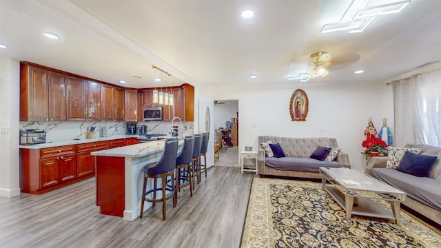 kitchen with light wood-type flooring, a kitchen bar, stainless steel microwave, and open floor plan