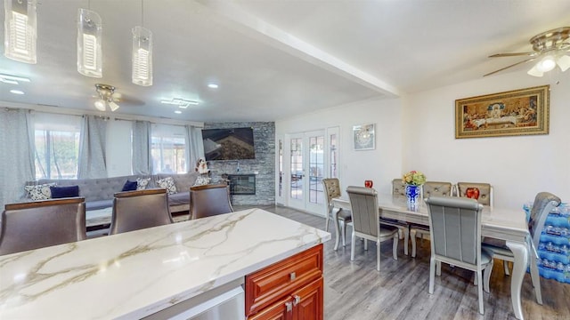 kitchen with light stone countertops, light wood finished floors, a fireplace, and a ceiling fan