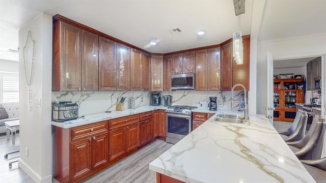 kitchen with tasteful backsplash, visible vents, appliances with stainless steel finishes, light stone counters, and a sink